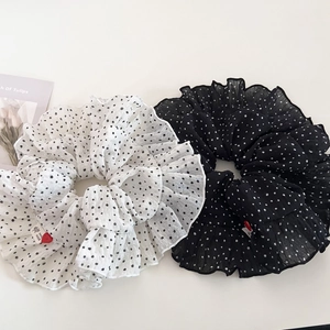 Close-up of black and white polka dot scrunchies with ruffled edges and handmade tags