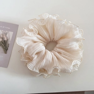 Detail shot of a large cream-colored chiffon hair scrunchie with layered ruffle edges