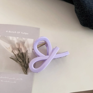 Detail of light purple glossy claw clip with twisted design on tulip card background