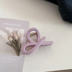 Detail view of a lavender twisted hair claw clip with a glossy finish on a white surface