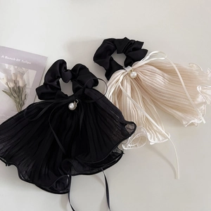 Detail of elegant ruffled hair scrunchies in black and beige with pearl charms
