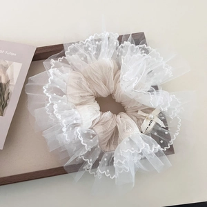 Elegant white lace scrunchie with pearl and bow detail on a rustic wooden tray