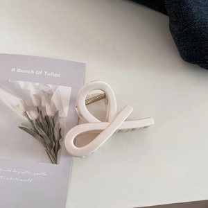 Detail view of large cream-colored shark hair claw clip with minimalist twisted design