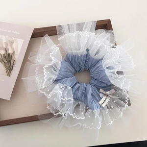 Detail of blue pleated hair scrunchie with white polka dot lace, pearl, and bow