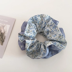Detail view of double-sided blue floral and solid color hair scrunchie on desk