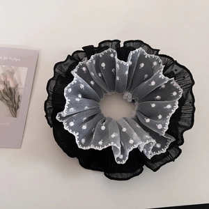 Detail of elegant black and white layered lace scrunchie with delicate polka dot embroidery