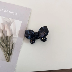 Macro shot of blue marble acetate butterfly hair clip with gold logo and crystals