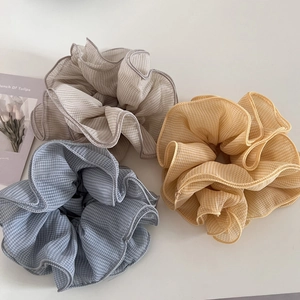 Close-up of 3-piece set of tiered plaid chiffon scrunchies in blue, grey, and yellow