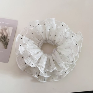 Detailed shot of white polka dot lace scrunchie with elegant silver stitched edges