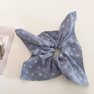 Detail view of misty blue scrunchie with white floral pattern on cotton fabric