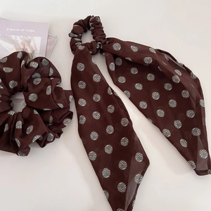 Close-up of brown polka dot chiffon scrunchie and matching ribbon hair tie accessory