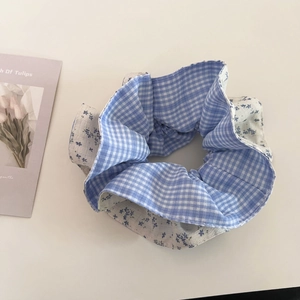 Detailed close-up of blue plaid and floral pattern scrunchie with a soft cotton texture