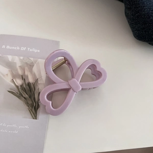 Detail showing lavender bow-shaped hair claw clip with heart cutouts on a white surface