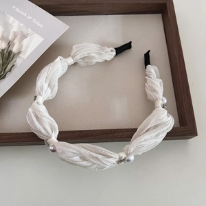 Détail d'un serre-tête en mousseline blanche plissée avec des perles et des strass