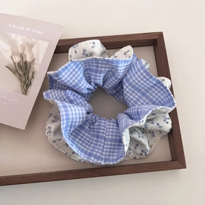 Detail of blue gingham and floral patchwork hair scrunchie in a wooden tray