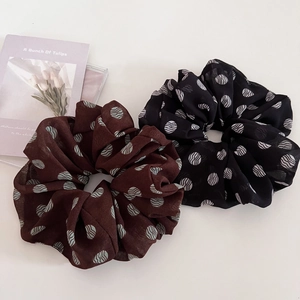Detailed close-up of brown and black chiffon hair scrunchies with wavy polka dot patterns