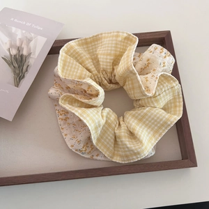 Detail of floral and plaid patchwork scrunchie on a wooden tray with a warm natural vibe