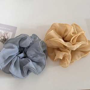 Close-up of oversized gingham chiffon scrunchies in light blue and yellow colors