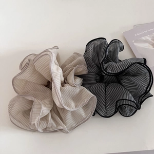 Detail of checkered chiffon hair scrunchies in beige and black with wave edges