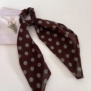 Close-up of brown polka dot scrunchie with streamers on a white clean background