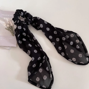 Close-up of black chiffon scrunchie with white polka dots and long floating ribbons