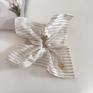 Elegante elastico per capelli a righe beige con ciondolo a fiocco dorato su fondo bianco