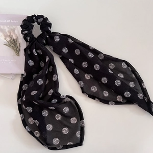 Close-up of black chiffon hair scrunchie with white wavy patterns and long elegant ribbons