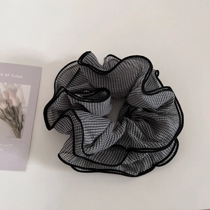 Detail of large checkered hair scrunchie with black wavy edges on white background