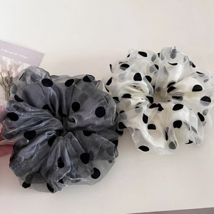 Close-up of fluffy polka dot mesh scrunchies in grey and beige with sheer texture