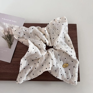 Dettaglio dell'elastico bianco a pois con elegante targhetta in metallo dorato