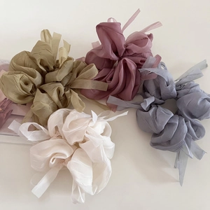 Detail of four sheer chiffon hair scrunchies with long ribbons in assorted soft pastel colors