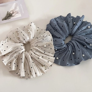 Detail of pleated polka dot scrunchies in cream and blue with pearl accents and silky texture