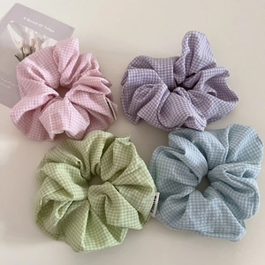 Dettaglio di quattro elastici per capelli a scacchi in rosa, viola, verde e blu