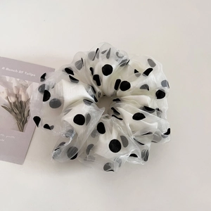 Detail of white organza scrunchie with black polka dots and semi-transparent texture