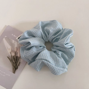 Dettaglio di un elastico per capelli a scacchi blu e bianchi con pieghe su sfondo artistico