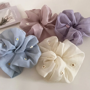 Gros plan sur quatre chouchous en organza avec broderies florales pastel
