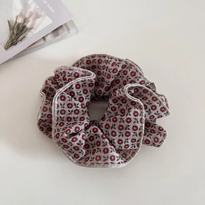 Detailed view of vintage floral scrunchie with red flowers on taupe fabric background