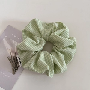 Dettaglio dell'elastico per capelli a quadretti verde chiaro e bianco in tessuto