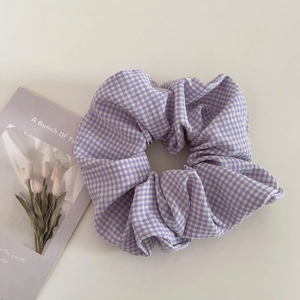 Vista dettagliata di un elastico per capelli in tessuto a quadretti viola e bianchi