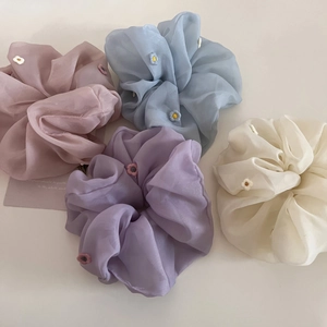 Vue détaillée de quatre chouchous transparents avec broderie florale en tons pastel