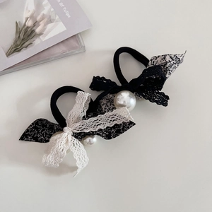 Close-up of floral lace bow hair ties featuring elegant white pearls and black fabric
