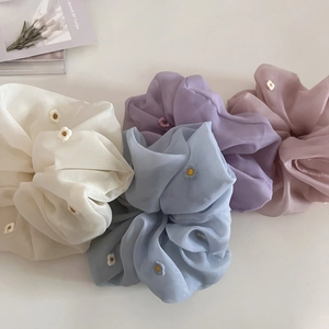 Vue détaillée de chouchous en organza brodés de fleurs en violet pastel, bleu et blanc