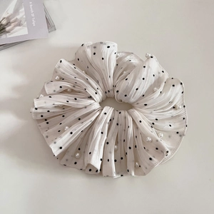 Detail of white pleated organza scrunchie with black polka dots and pearl accents