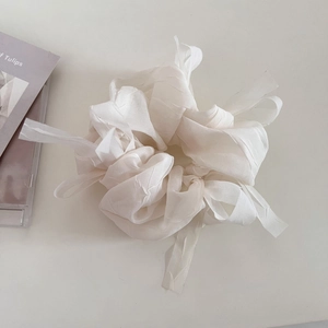 Detailed view of a white tulle scrunchie with long ribbons on a minimalist background