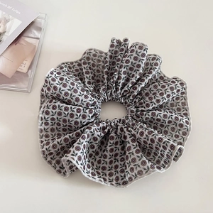 Detail of vintage floral scrunchie with ruffled edges on minimalist cream background