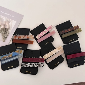 Set of retro acetate tortoiseshell hair clips on black cards over a clean white surface