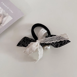 Close-up of lace floral bow hair tie with pearls and elastic band on a beige background