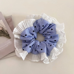 Blue striped scrunchie with heart print and white pleated edges on a minimalist background