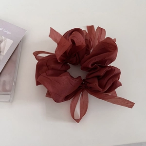 Detail view of a large burgundy chiffon hair scrunchie with long elegant ribbons on white background
