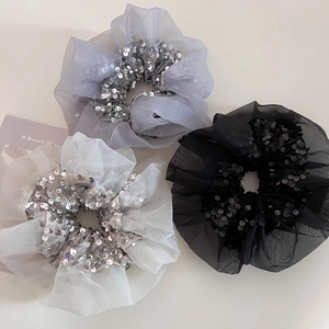 Detailed view of organza scrunchies in silver, beige, and black with shiny sequins